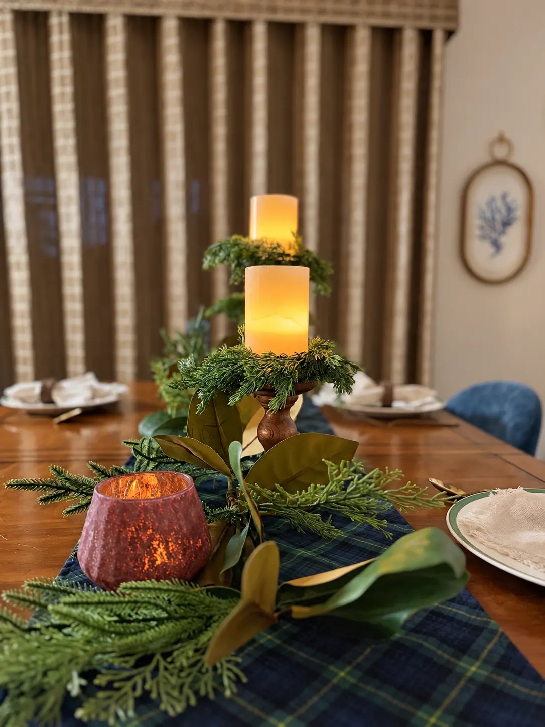 Candlelight glowing through the burgundy glass holder and turned wooden candle holders on the real winter table