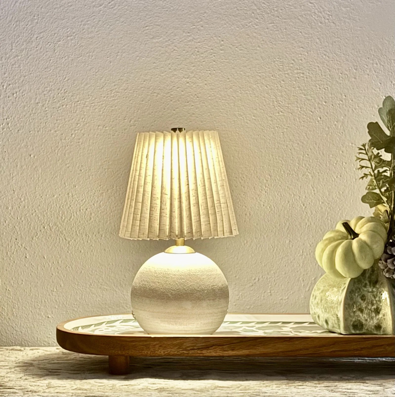 Pleated linen lamp glowing on a styled console tray, from the Golden Hour edit