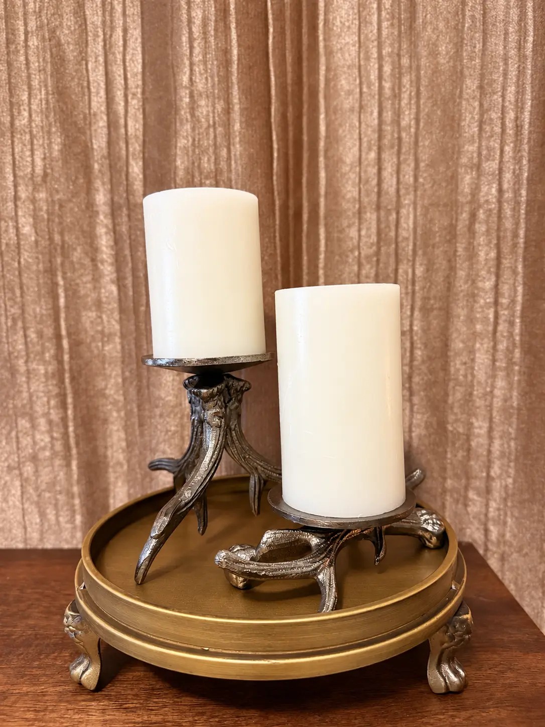 Small and tall aged-bronze antler candle holders styled together with ivory pillar candles on a tray