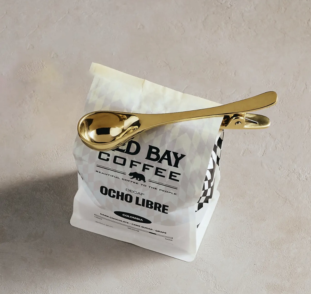 Brass coffee scoop with hinged bag clip fastening a bag of coffee
