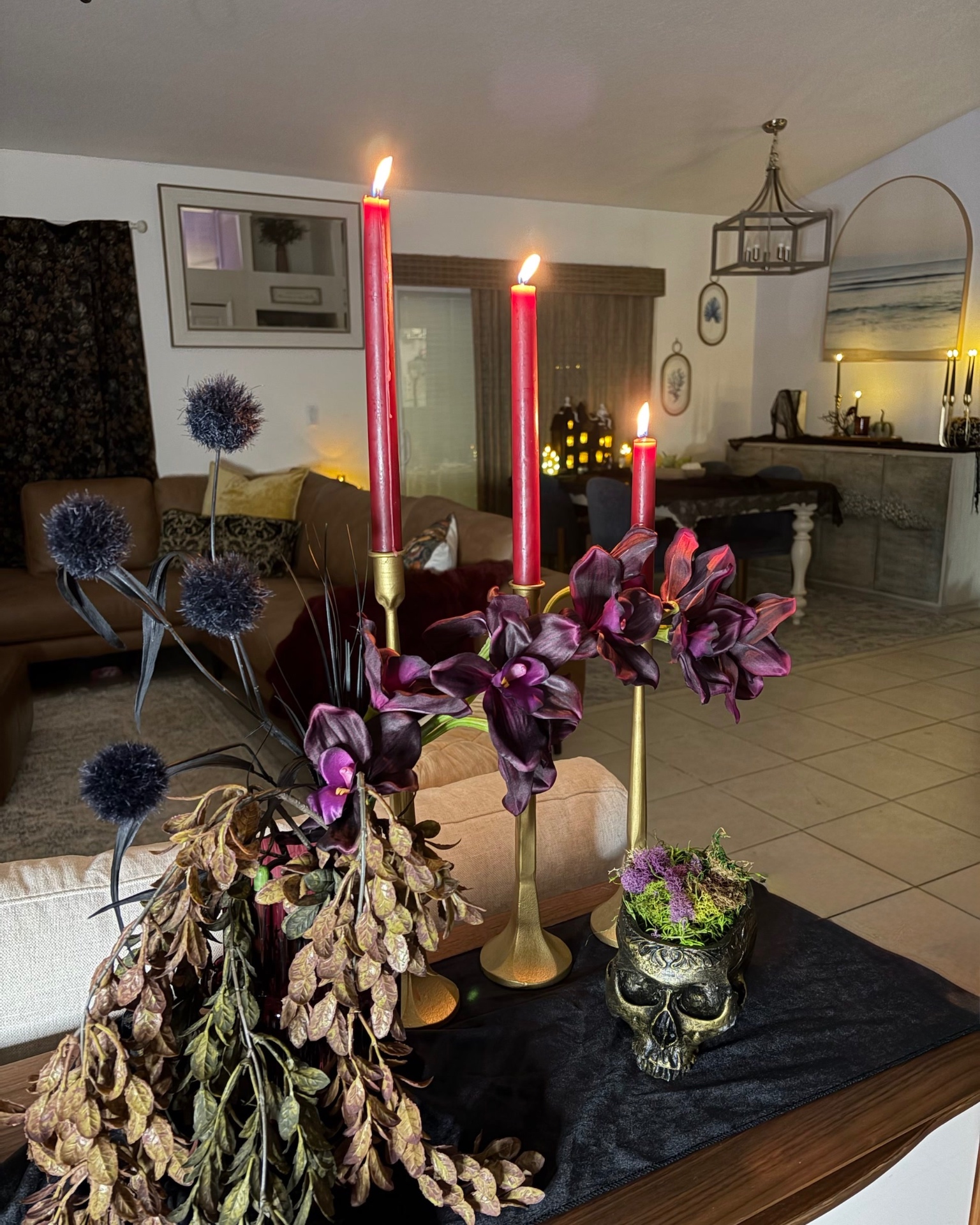 An alternate view of the After Dark arrangement with lit candles, plum orchids and a moss-filled skull planter