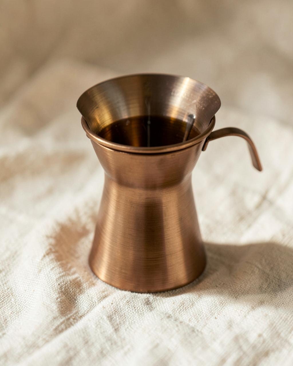 A styled counter detail with a bronze pour-over and stoneware