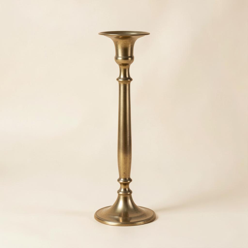 A tall antique brass candlestick on an ivory background