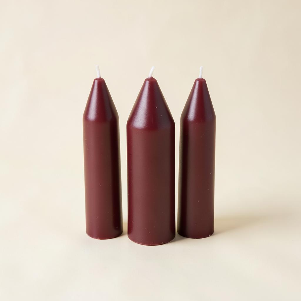 Three deep burgundy taper candles on an ivory background