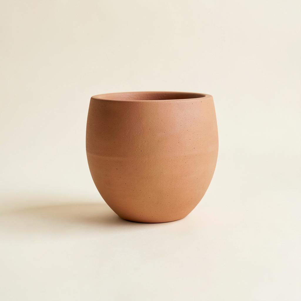 A matte warm clay stoneware vessel on an ivory background